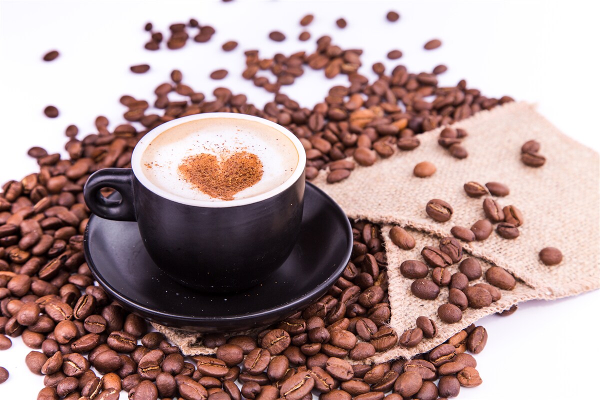 Papier peint grains de café éparpillés à côté d'une tasse de café
