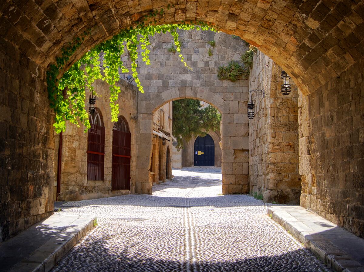 Papier peint Un arc en pierre menant à une ville ancienne