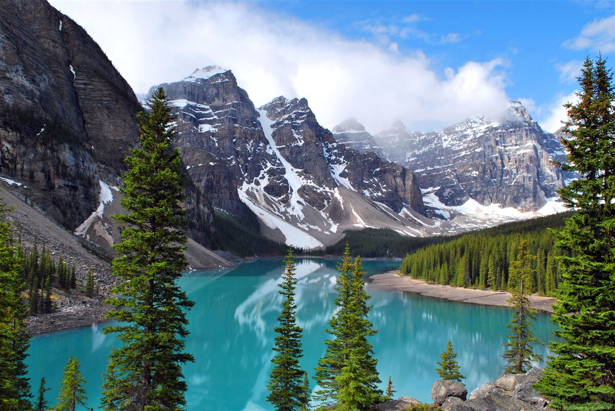 Papier peint un lac aux eaux bleues au pied de sommets montagneux