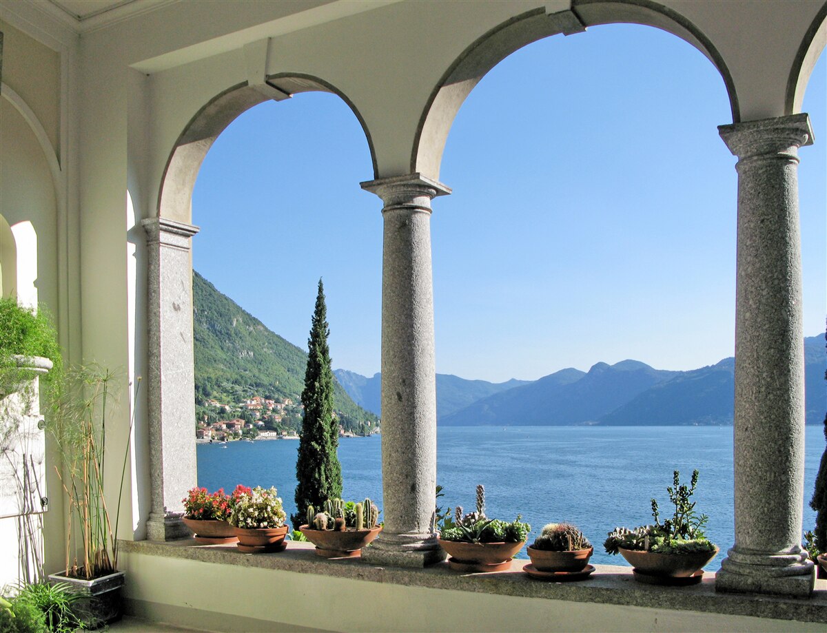 Papier peint balcon avec ouvertures cintrées et vue sur l'eau et les montagnes