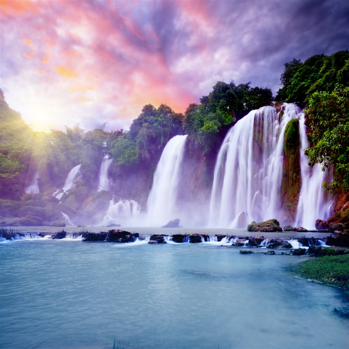 Papier peint une énorme chute d'eau en cascade sur fond de coucher de soleil