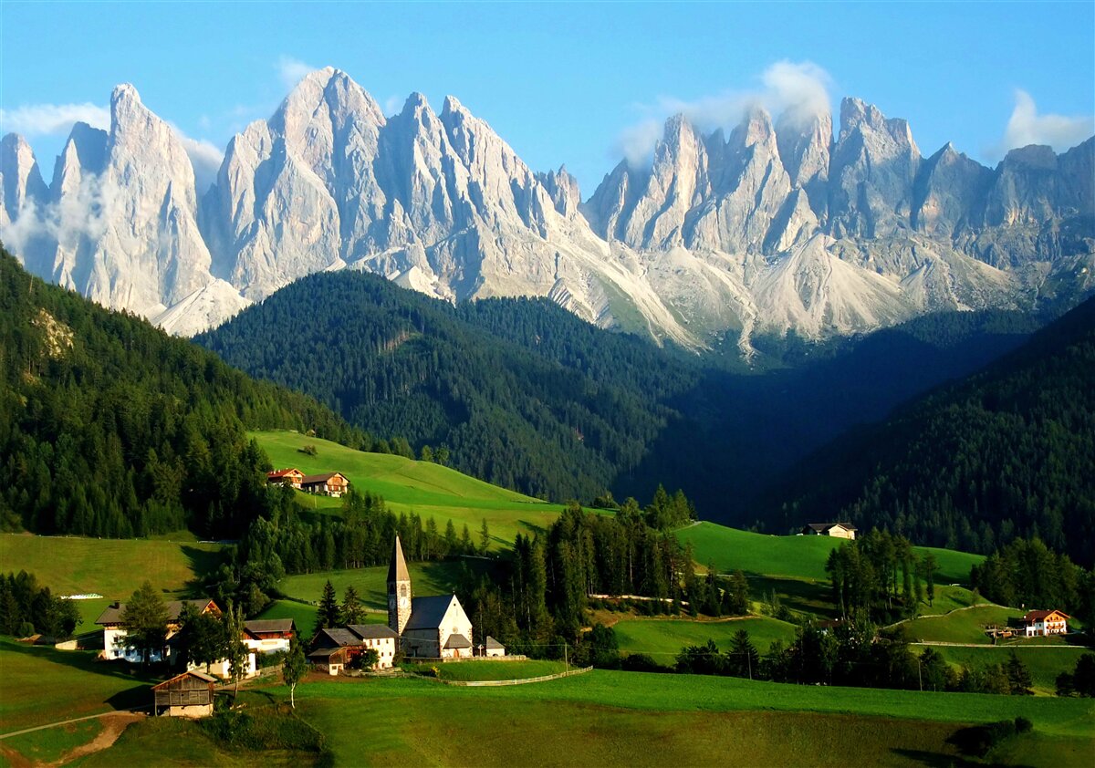 Papier peint village dans une clairière au pied des montagnes