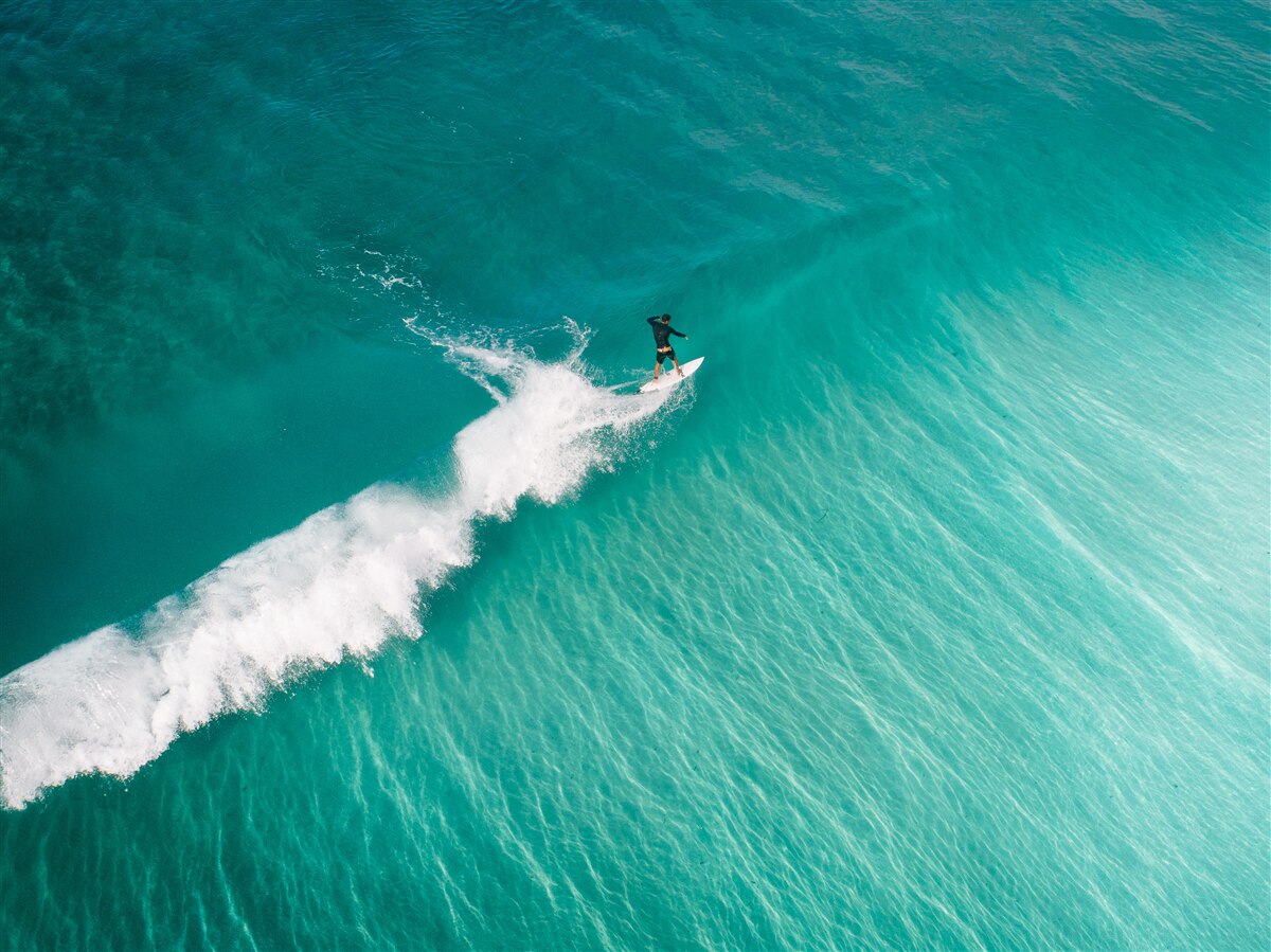 Papier peint un surfeur solitaire dans l'immensité de l'océan